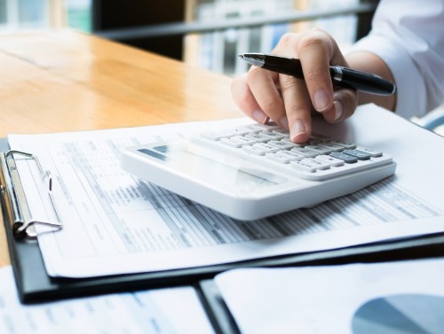 Man using calculator at desk with documents