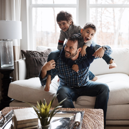 Dad playing with sons in living room